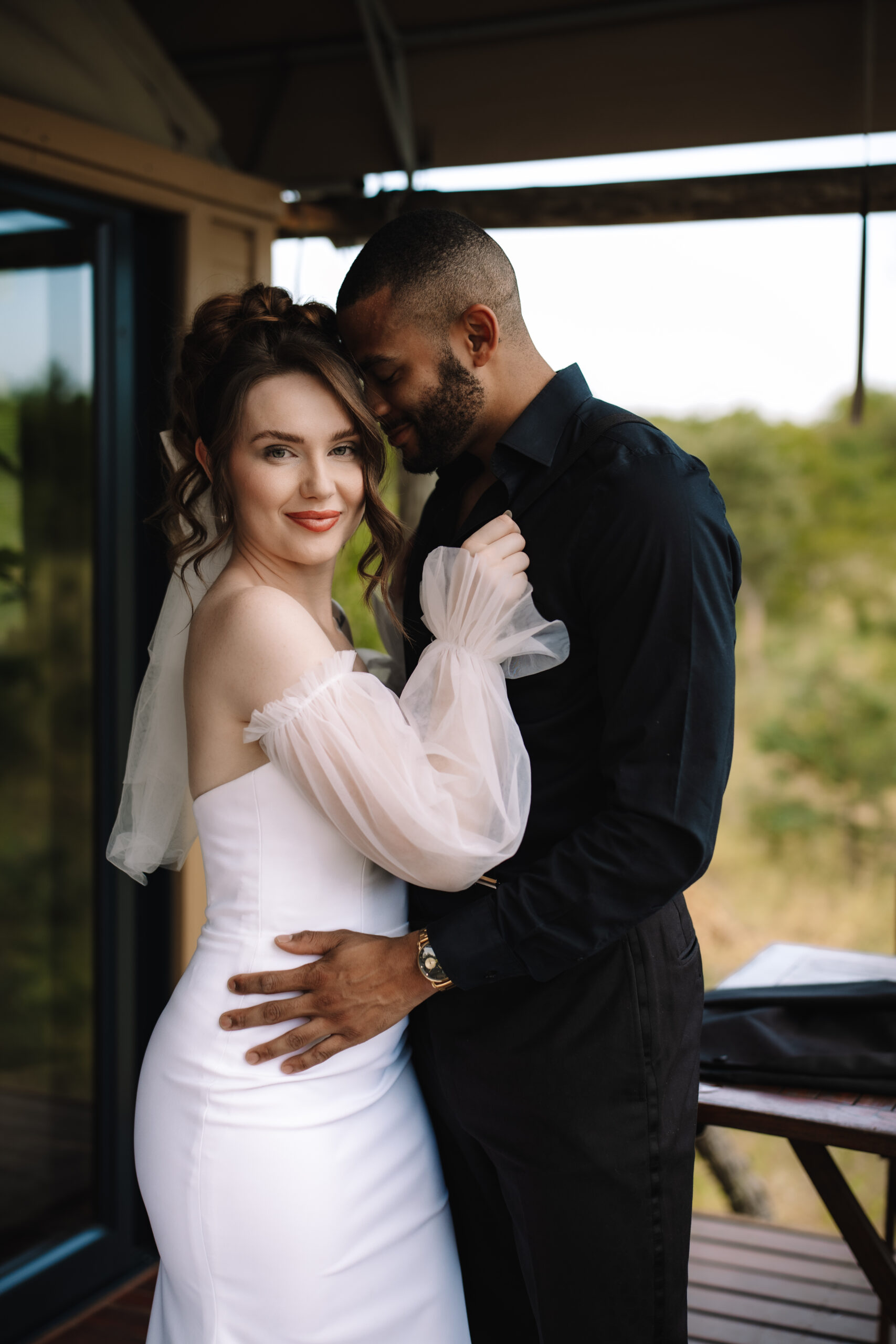 Bride and groom embracing on a private lodge deck overlooking the bush during a safari elopement in Africa