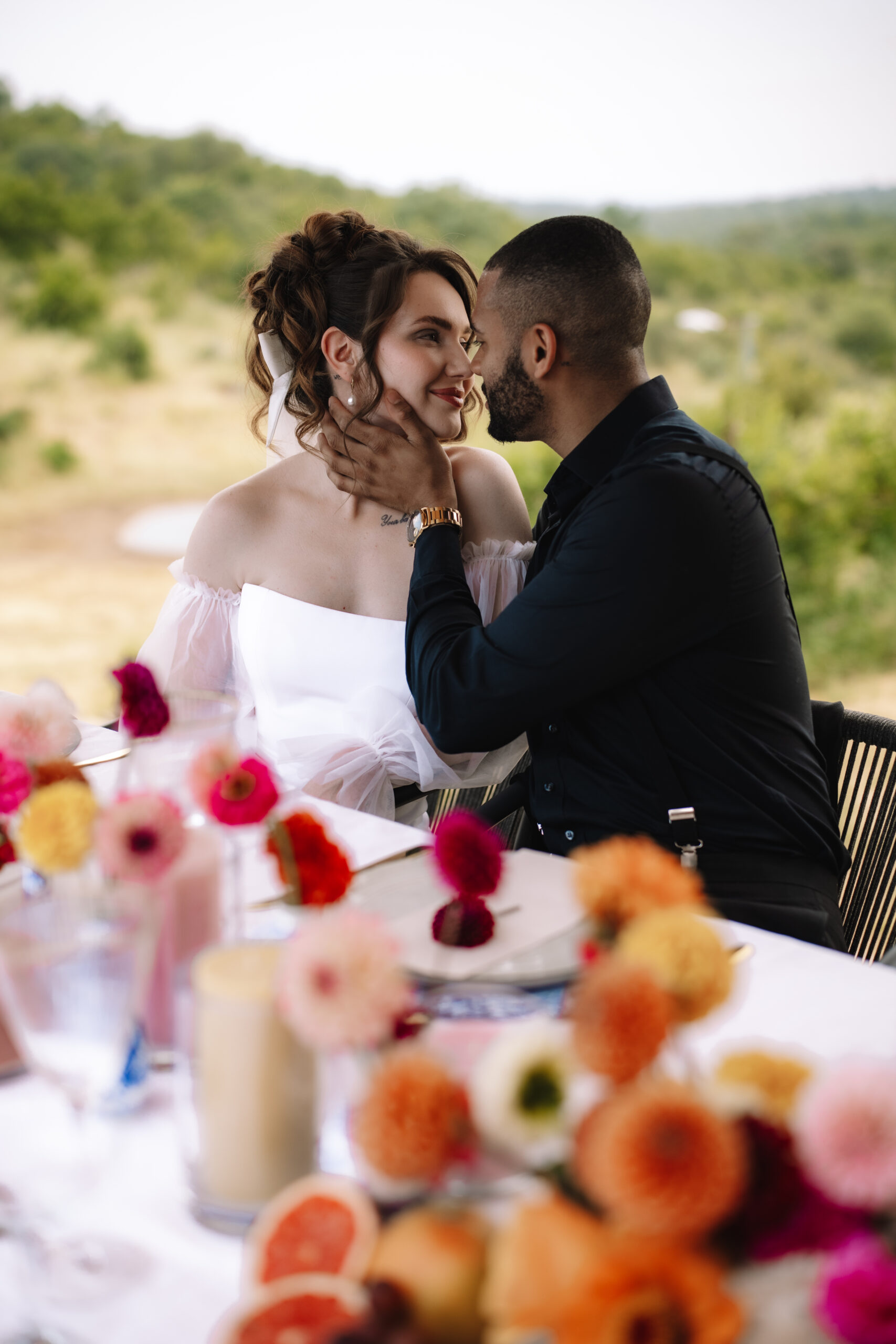 Bride and groom sharing a quiet moment at their safari lodge table surrounded by florals and nature views