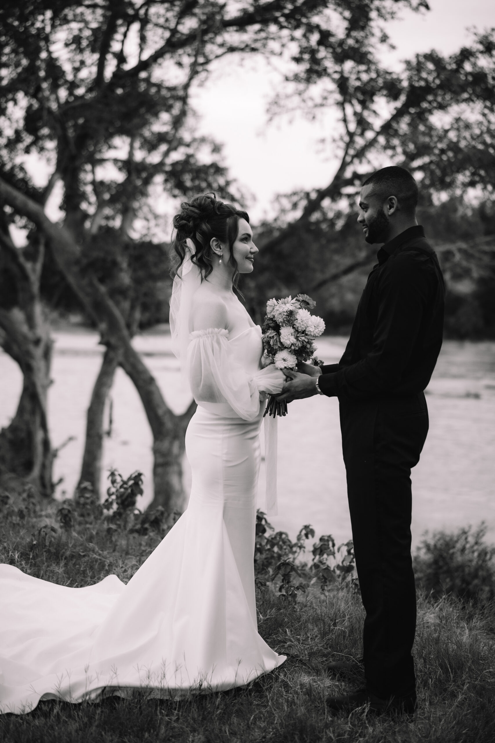 Black and white photo of bride and groom exchanging vows beside a river during their South Africa elopement
