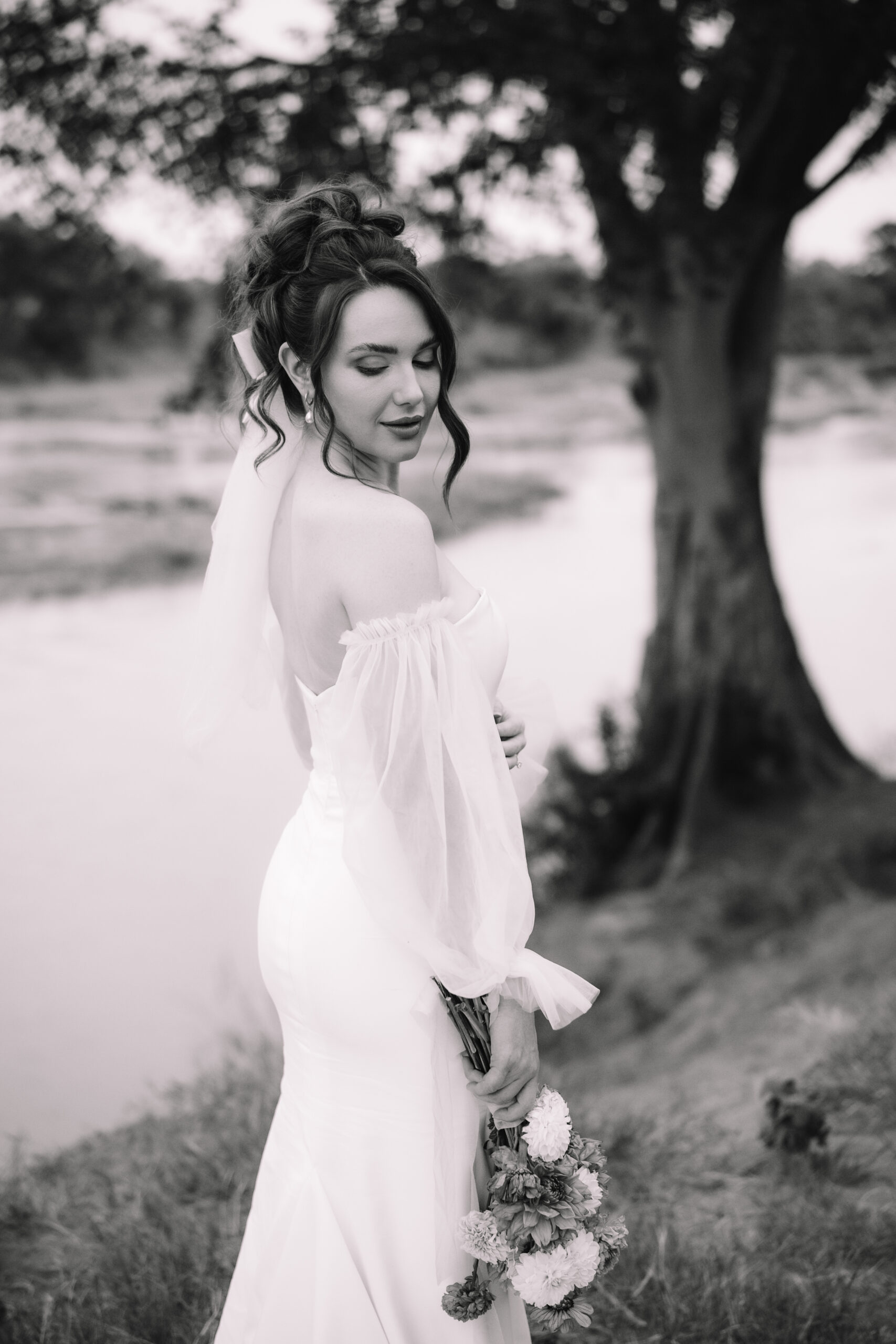 Black and white portrait of bride holding her bouquet near the river on her elopement day