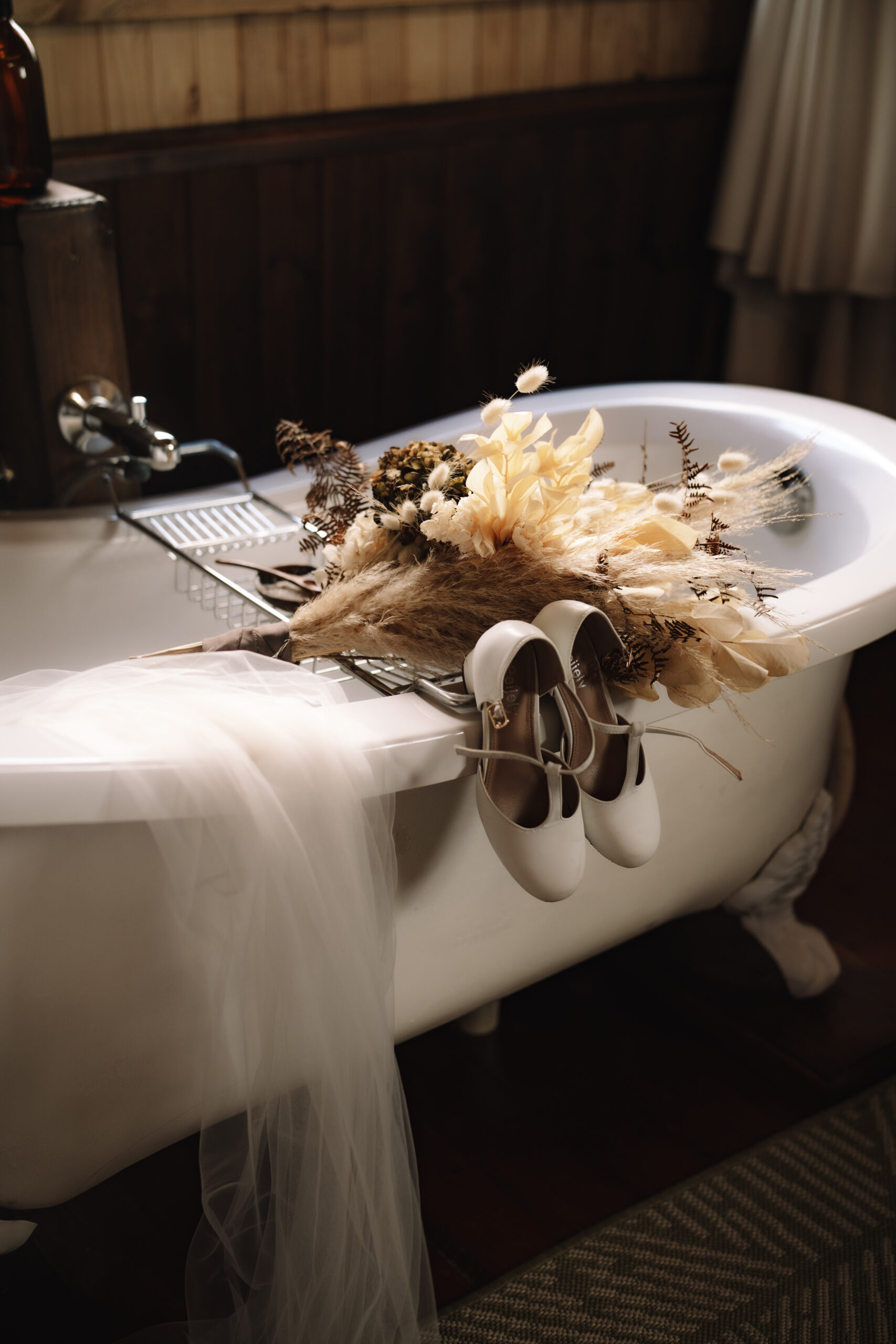 Wedding bouquet and bridal shoes resting on a vintage bathtub inside a safari lodge suite