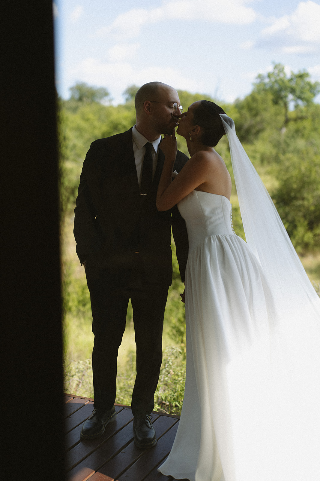 Bride kissing groom on safari lodge deck during intimate elopement portraits
