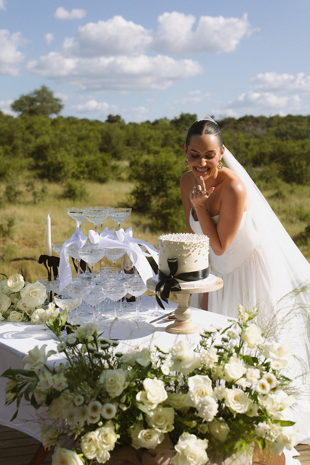 Bride smiling beside champagne tower and wedding cake during celebration after they elope in South Africa
