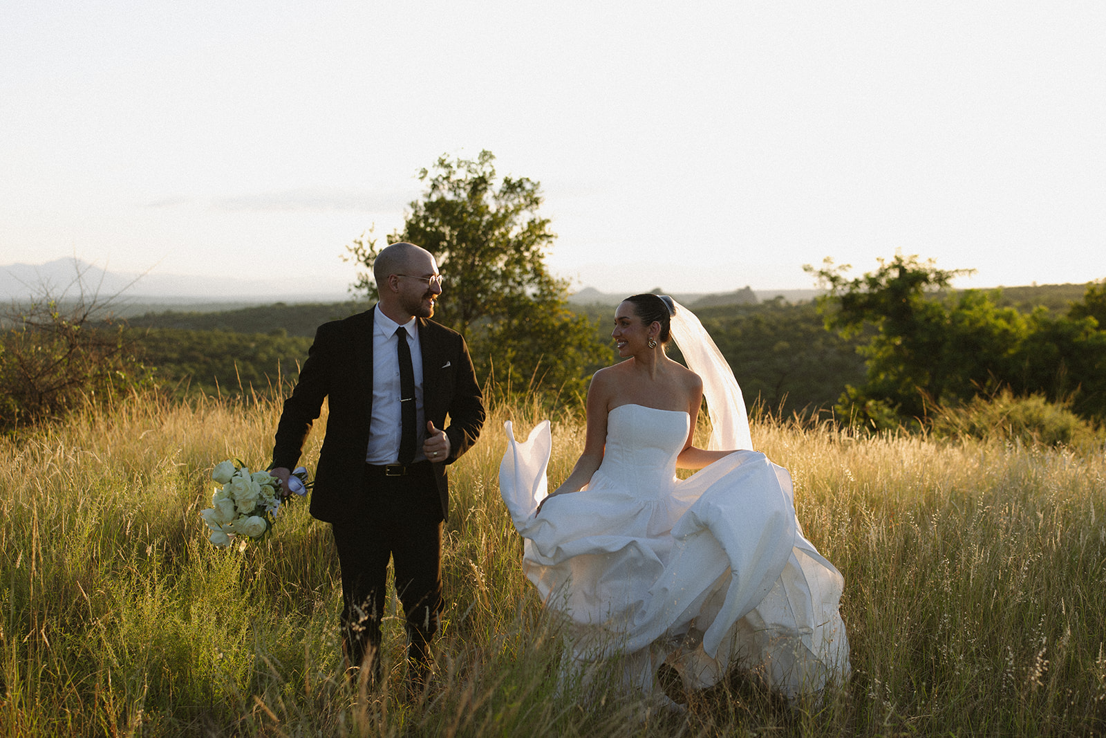 Bride and groom walking through golden grasslands during sunset portraits after they elope in South Africa
