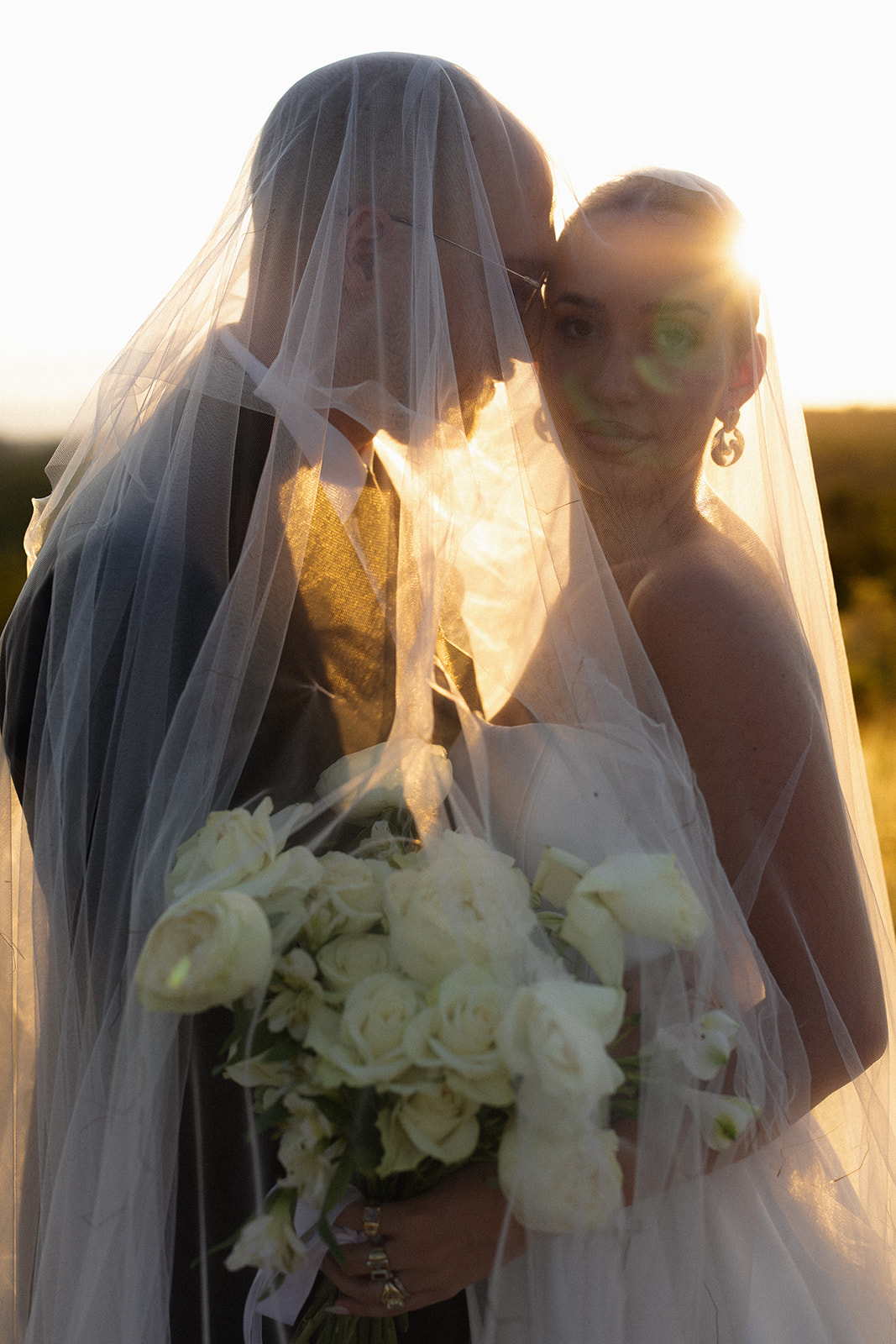Backlit bridal portrait through veil with bouquet during golden hour after they elope in South Africa
