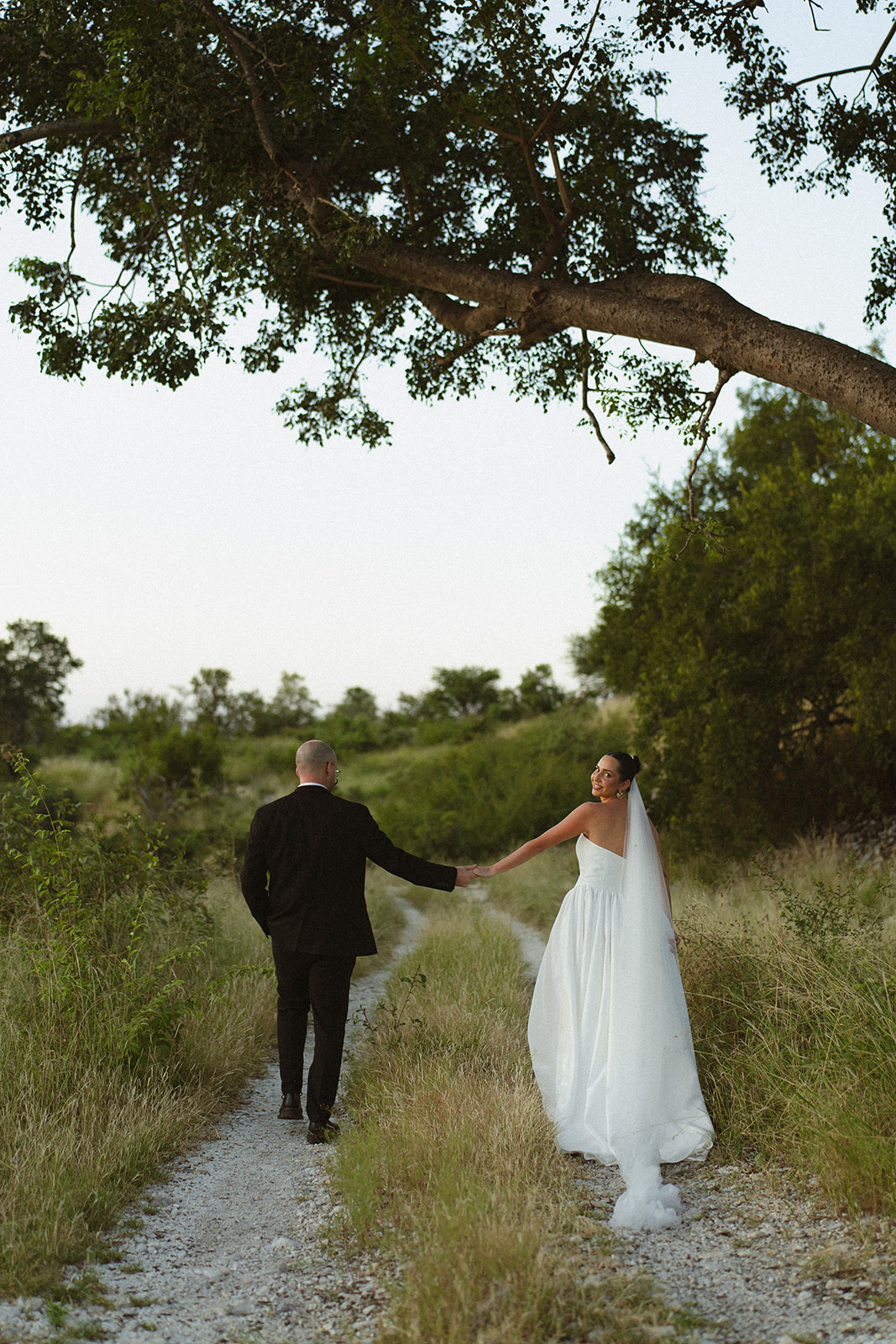 Bride and groom walking hand in hand down bush path after they elope in South Africa
