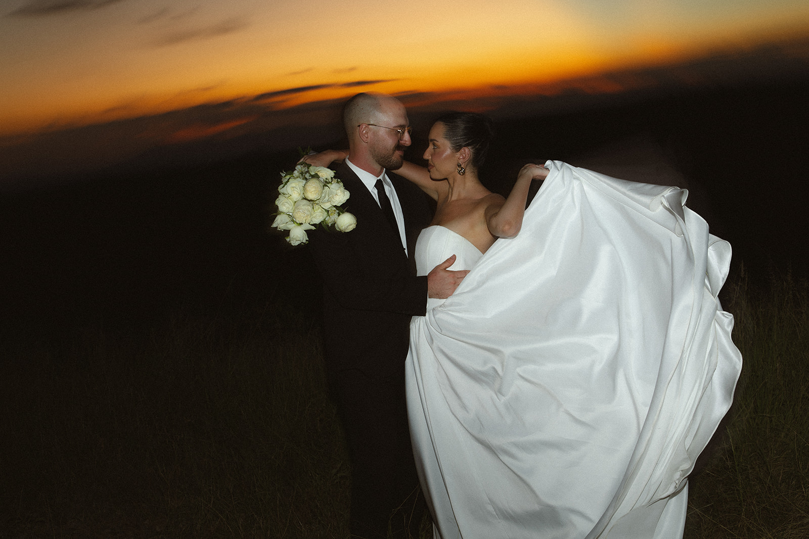 Bride and groom embracing at sunset with flowing dress during romantic safari elopement
