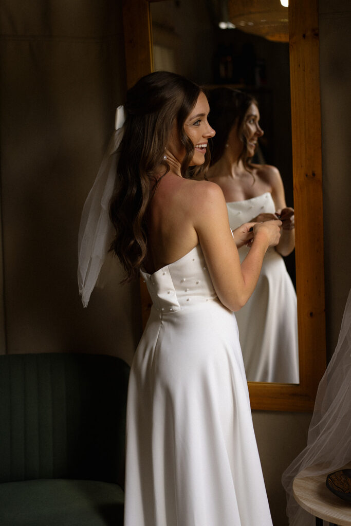 Bride smiling while getting ready in safari lodge mirror before intimate elope in South Africa
