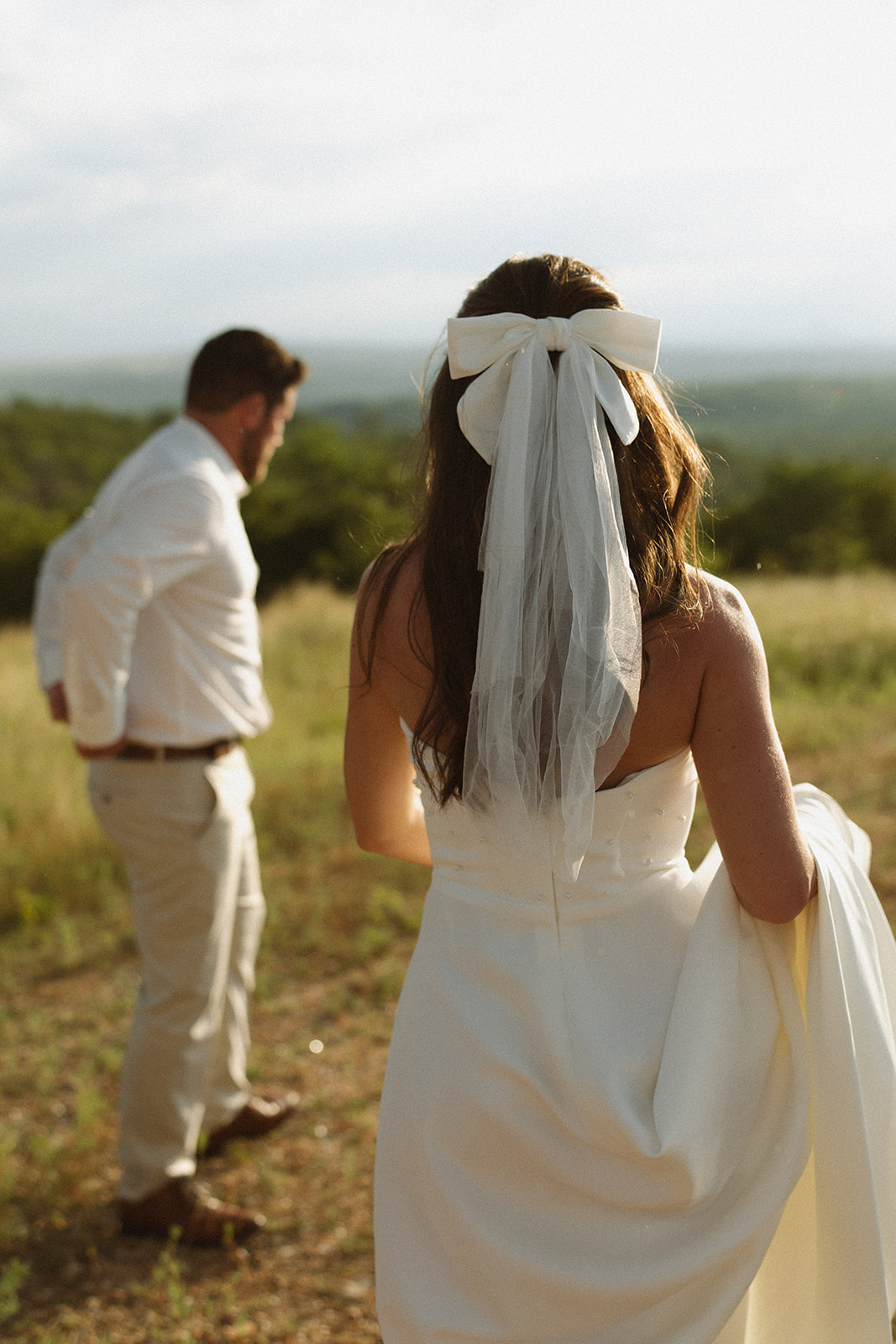 Bride with bow veil looking out over African landscape after they elope in South Africa
