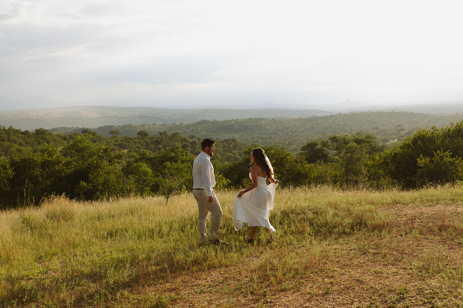Couple dancing on hilltop overlooking the bush after they elope in South Africa

