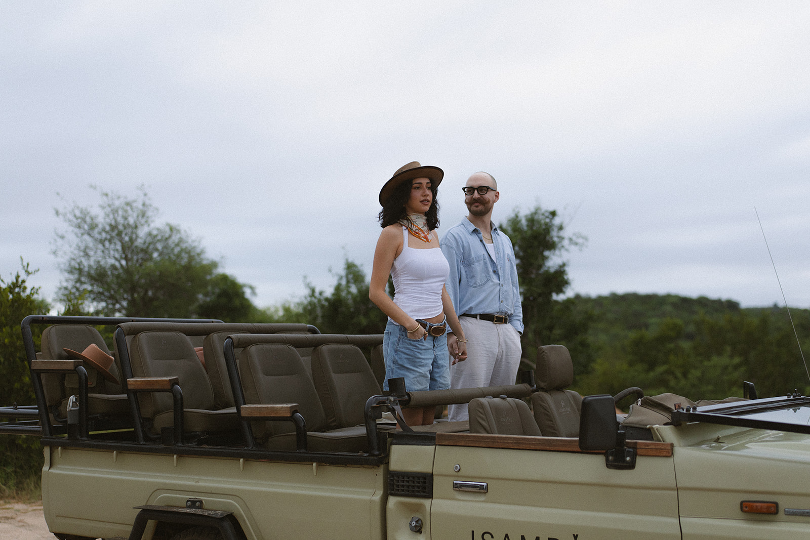 Couple standing together in an open safari vehicle overlooking the African bush during a romantic post-wedding safari experience.
