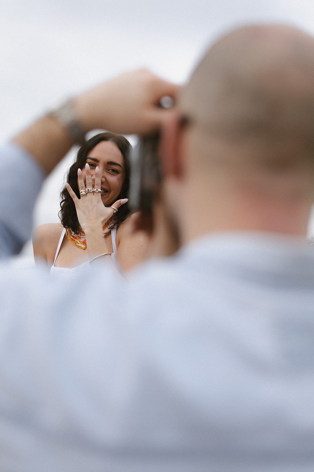 Bride showing her engagement ring while her partner photographs her during their safari adventure engagement session in South Africa.

