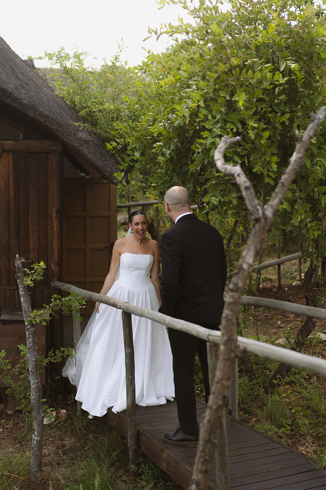 Bride and groom sharing a joyful first look on a wooden walkway outside a safari lodge during an intimate Africa weddings celebration.
