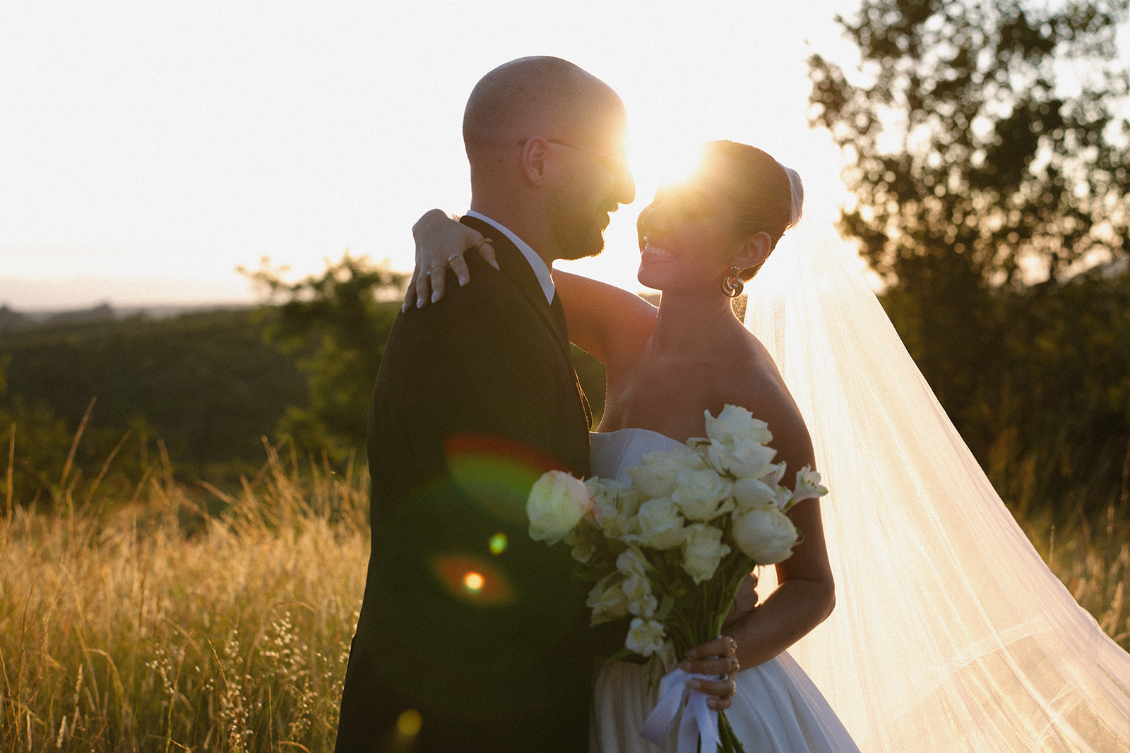 Bride and groom embracing at golden hour with glowing sunset light during romantic Africa weddings portraits in the savanna.
