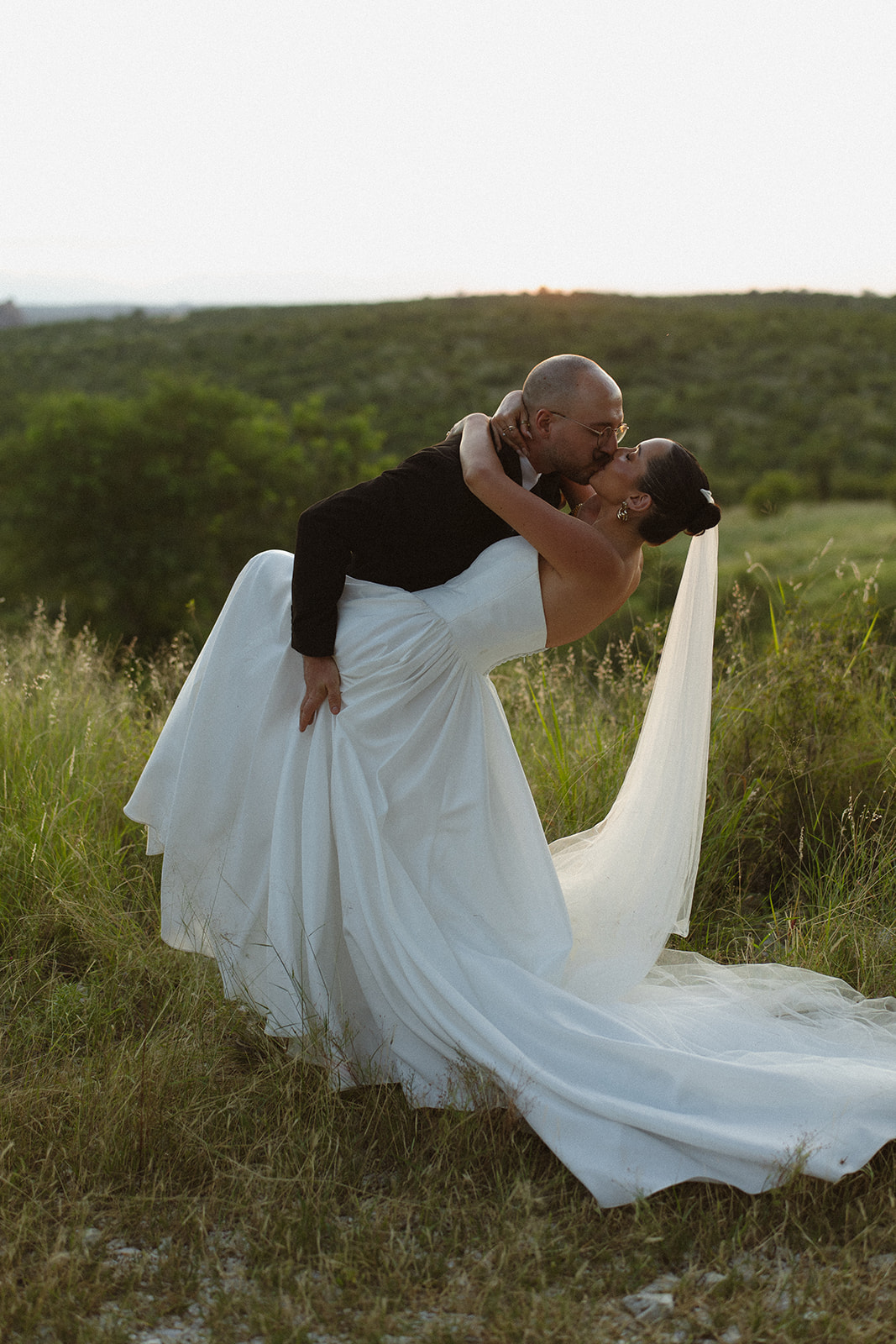 Groom dipping his bride for a kiss in the African savanna during golden hour wedding portraits.
