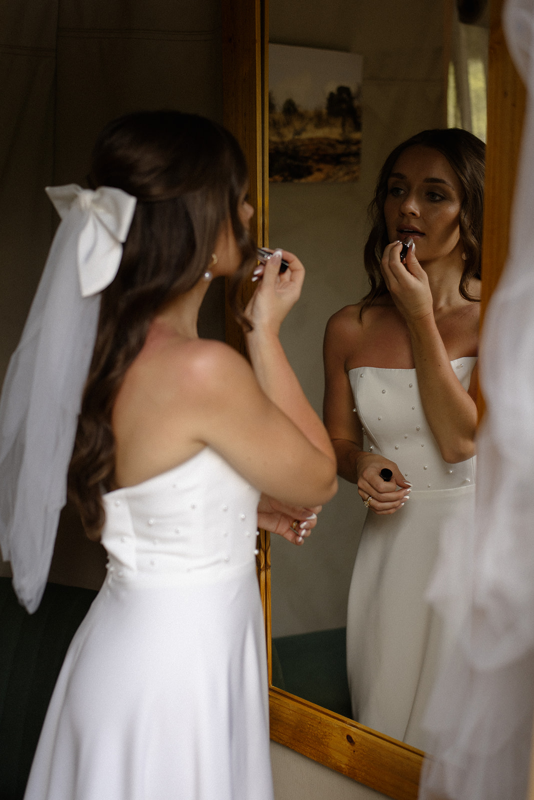 Bride applying lipstick in mirror inside safari lodge while getting ready for her wedding day as part of safari wedding packages