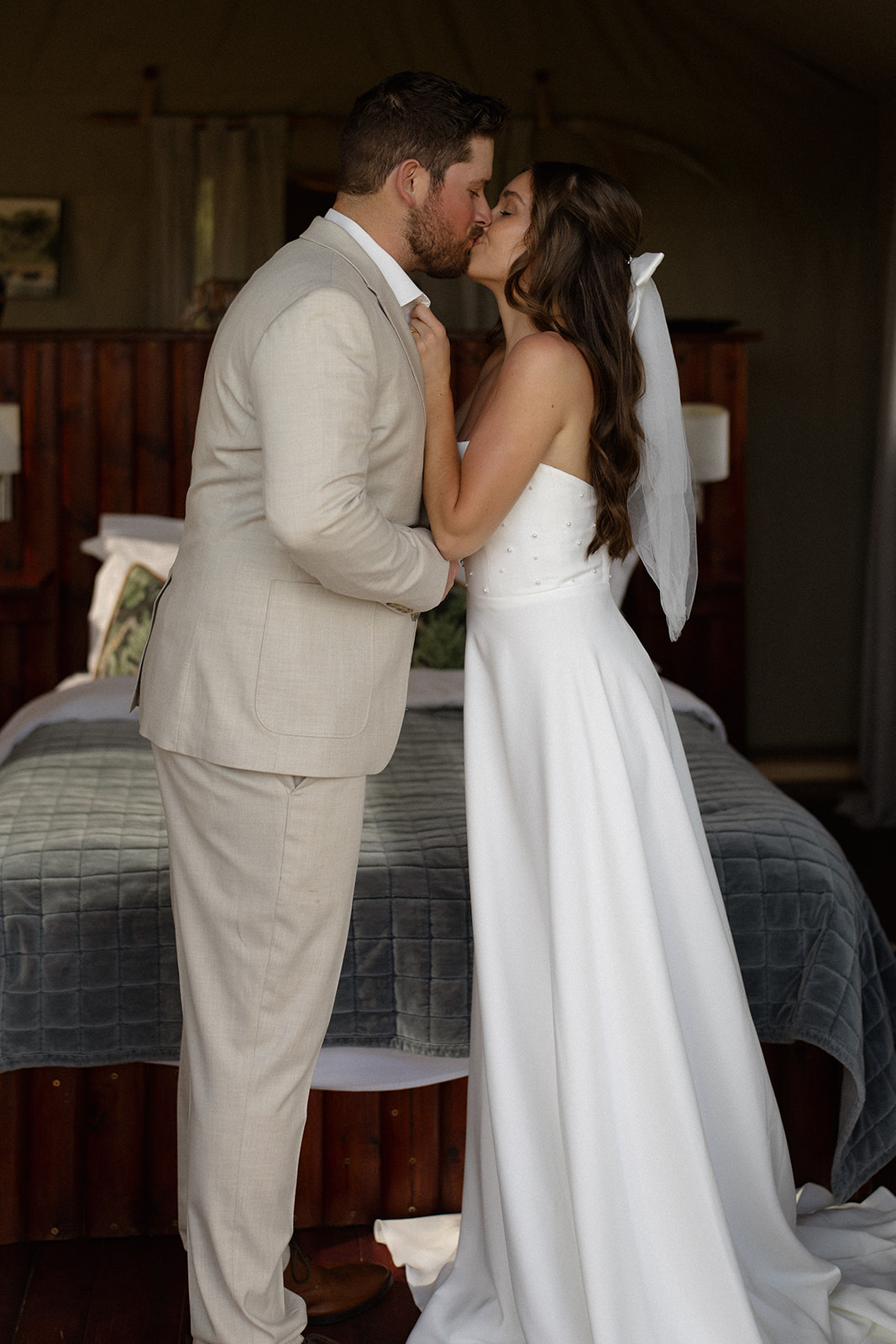 Bride and groom sharing a romantic kiss inside a luxury safari lodge bedroom during their wedding morning
