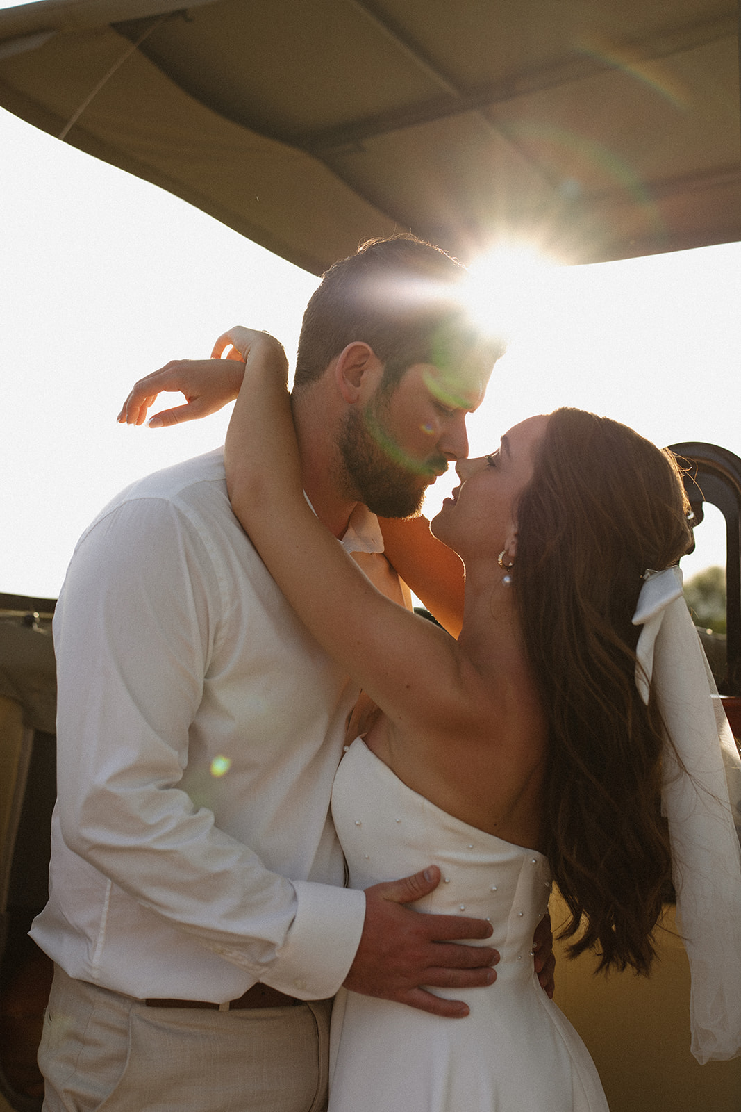 Bride and groom embracing in golden backlight on a safari vehicle during a romantic safari wedding packages experience
