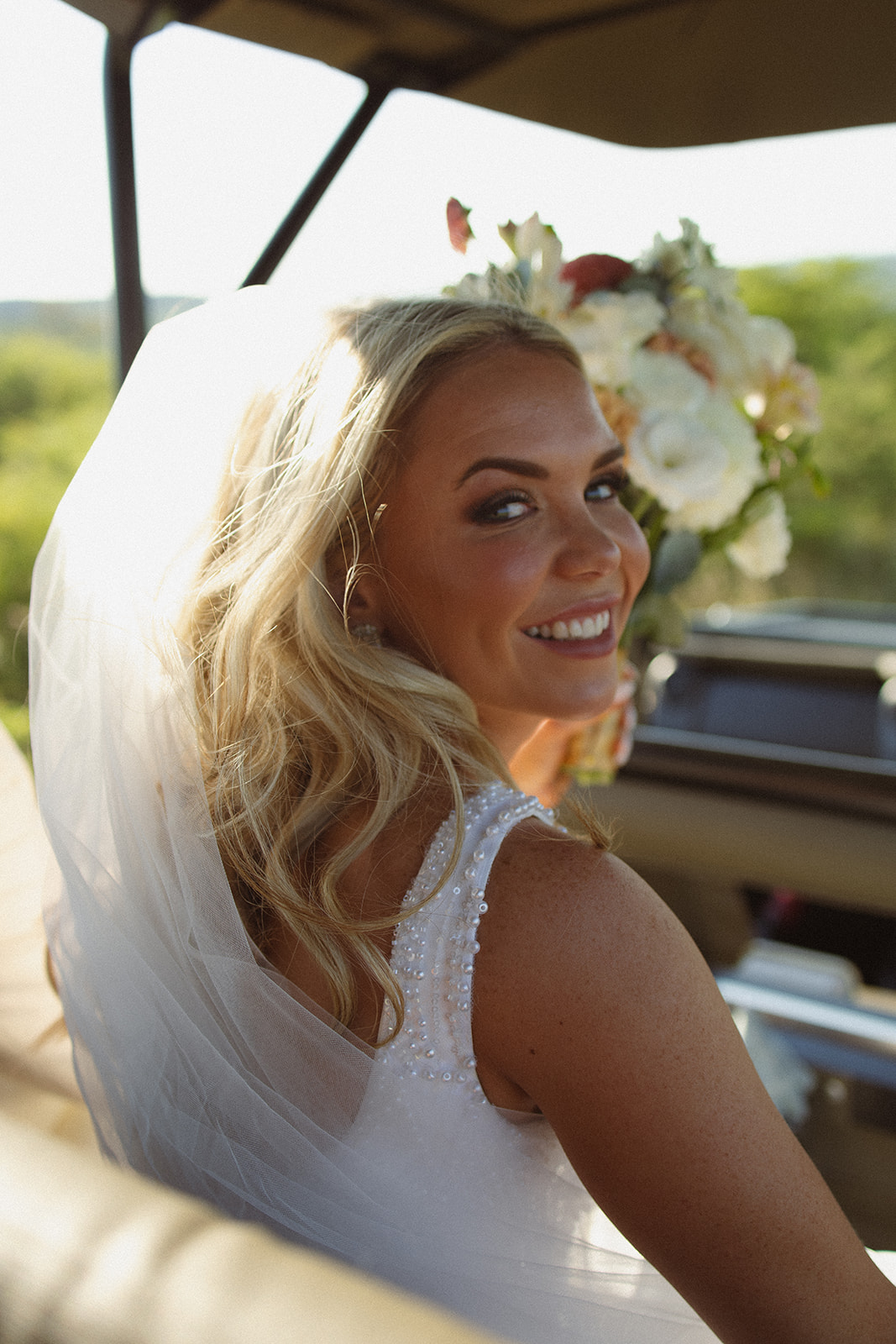 Bride smiling in safari vehicle during golden hour after wedding ceremony in South Africa