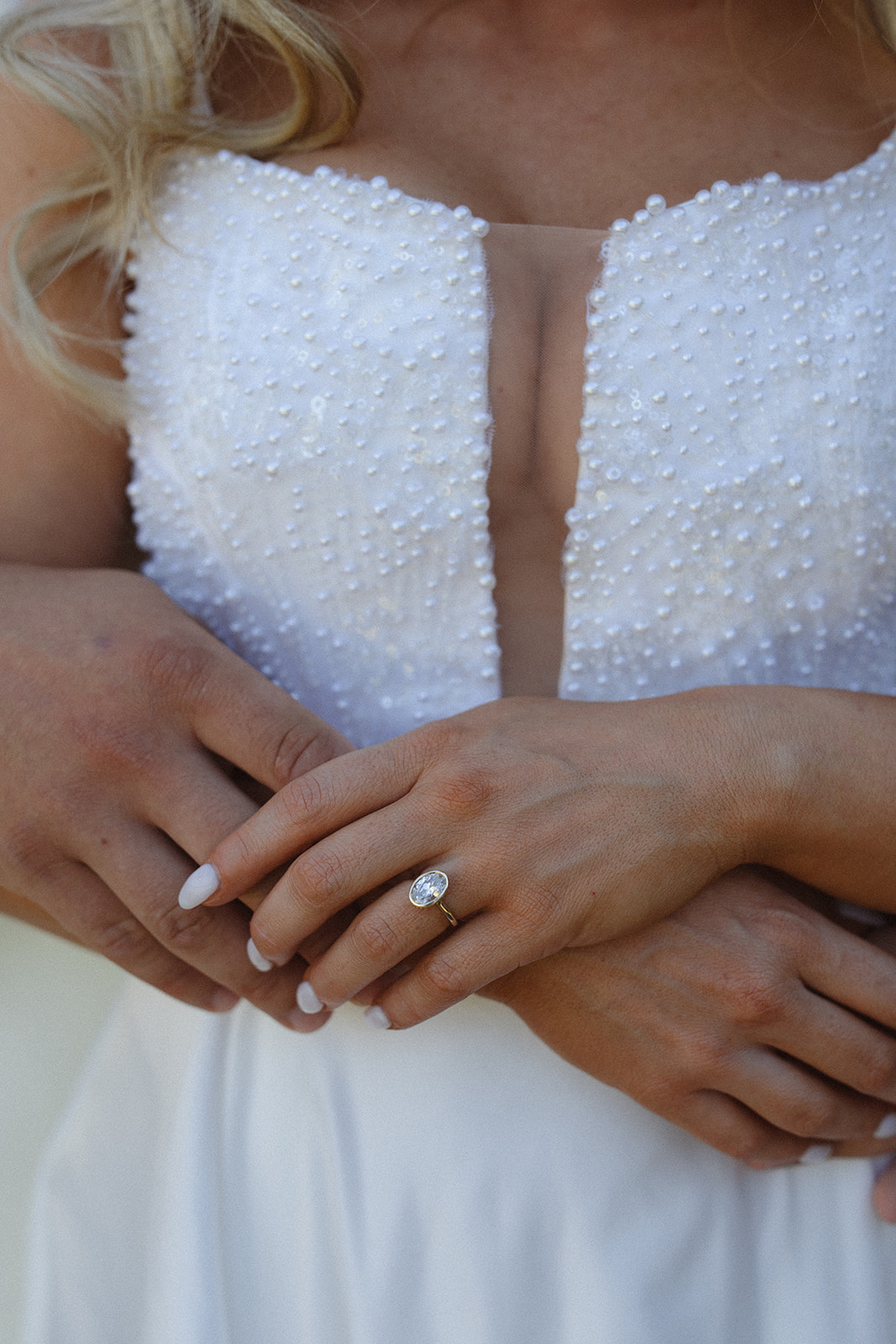 Close-up of bride’s engagement ring and dress detail during wedding day