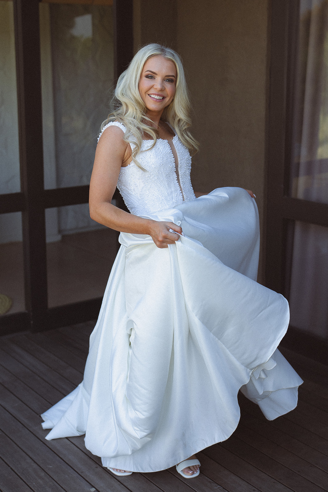 Bride smiling and holding dress on lodge deck before ceremony in South Africa