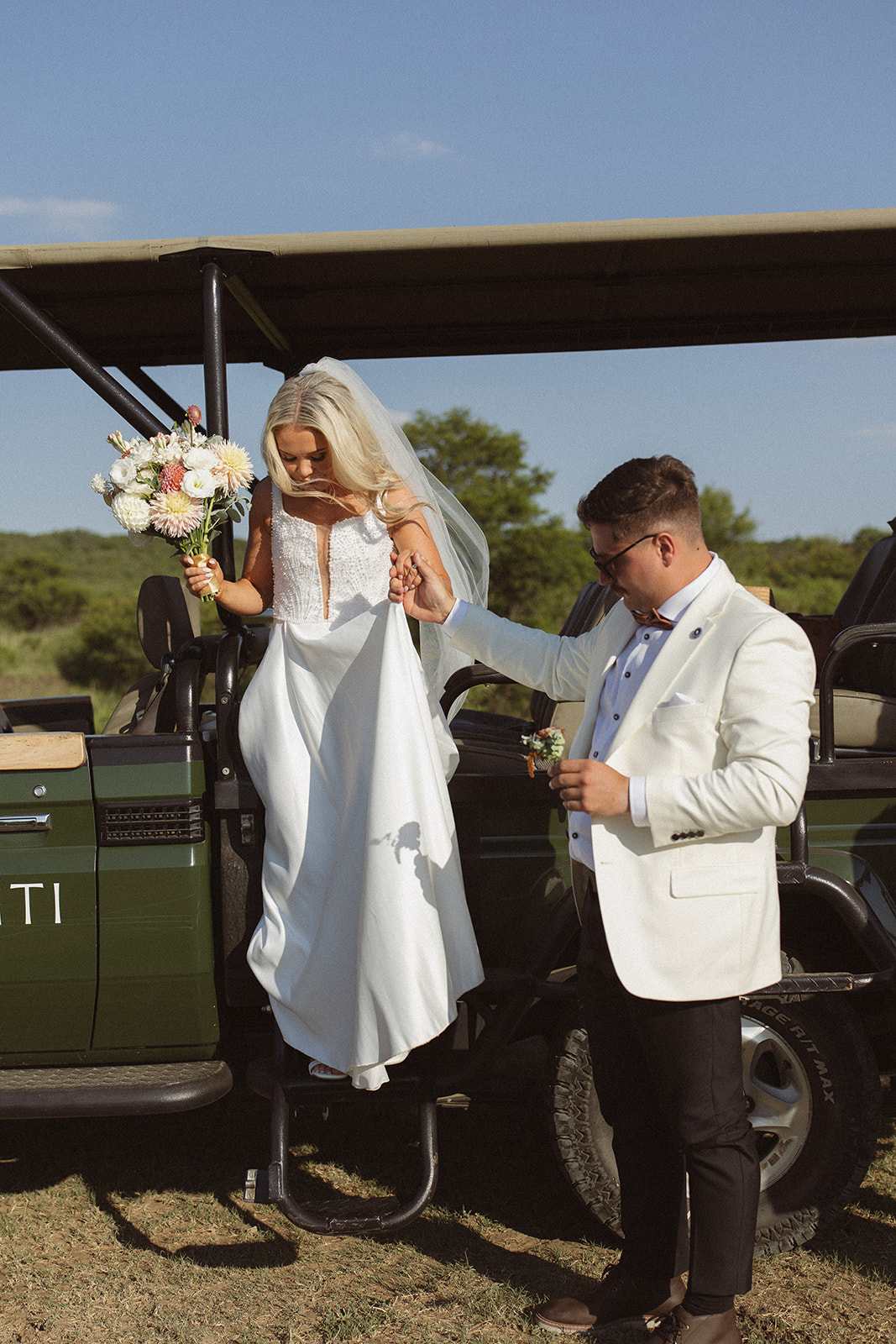Bride stepping out of a safari vehicle with groom helping her during a South Africa safari wedding day