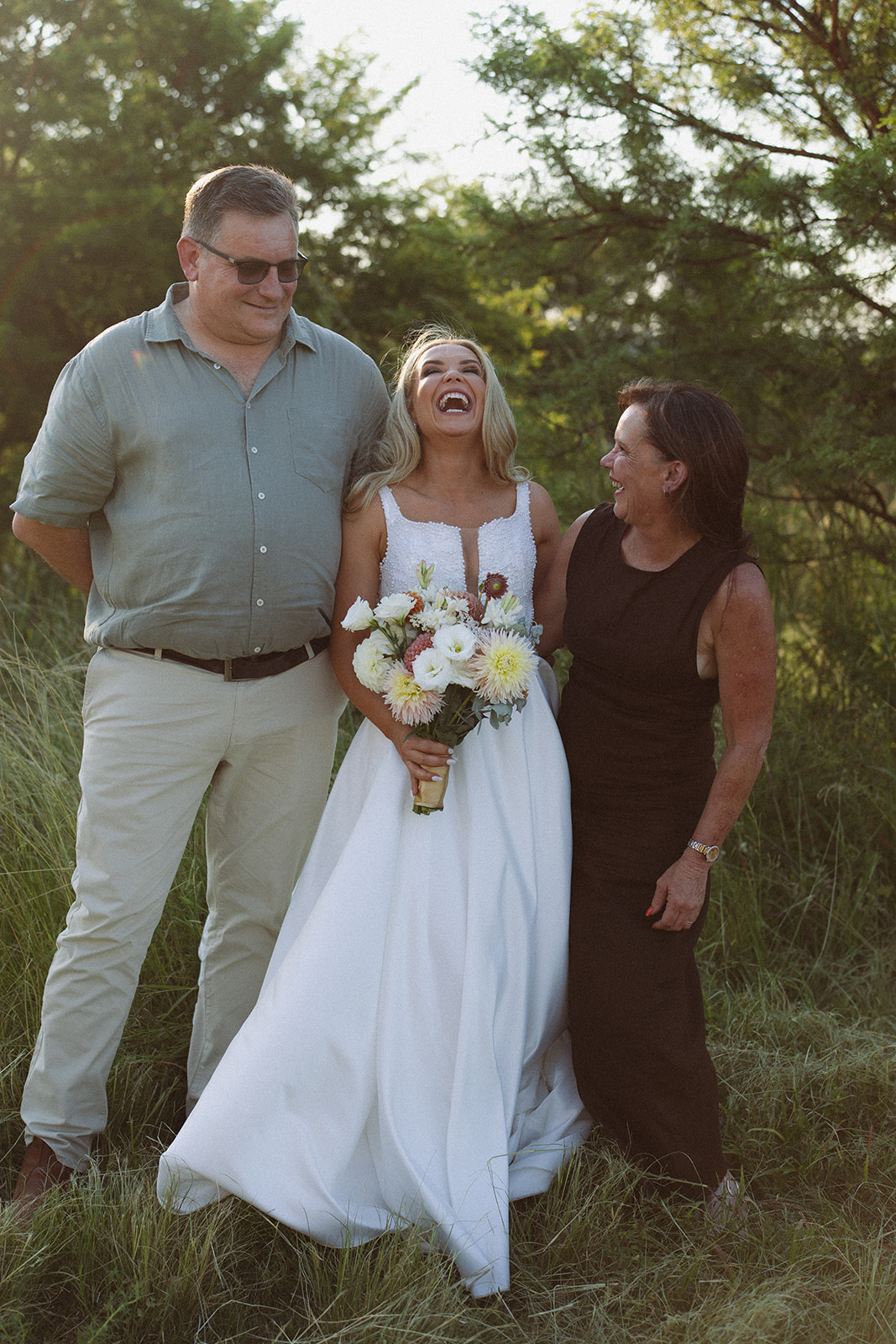 Bride laughing with her parents in the grass during an intimate safari wedding in South Africa