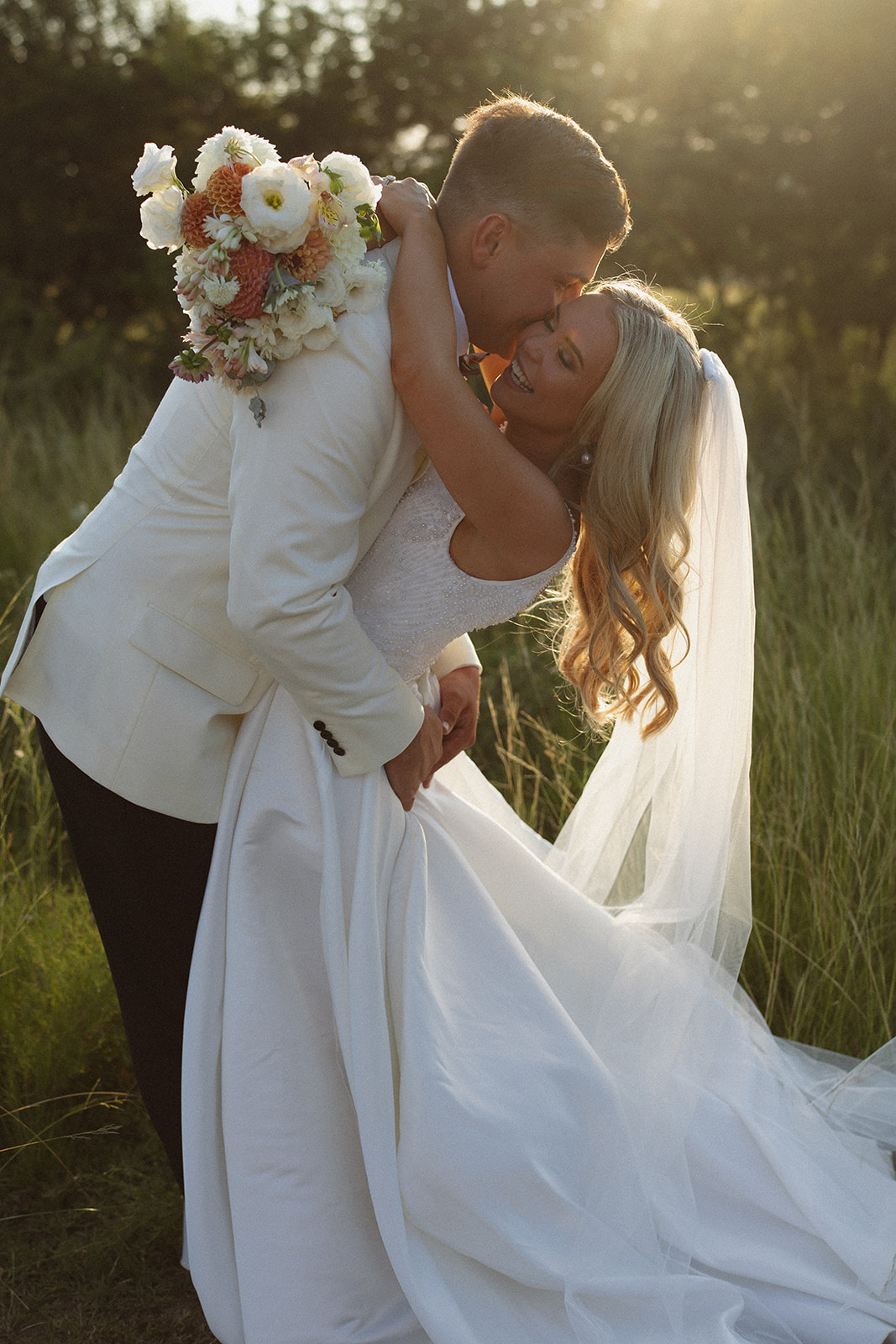 Groom dipping bride in tall grass during sunset at a safari wedding in South Africa