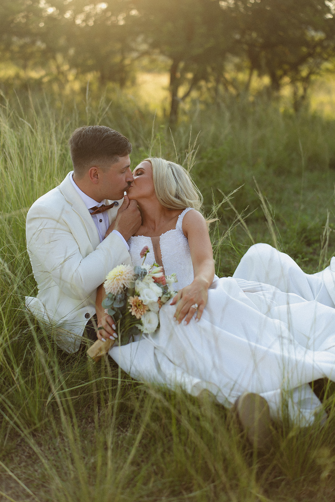 Bride and groom kissing in tall grass during golden hour at a safari wedding in South Africa