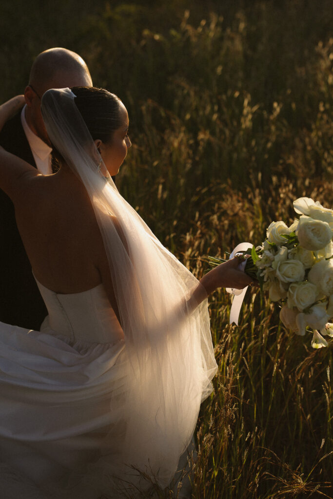 Bride and groom embracing in golden grass at sunset during their South Africa safari elopement