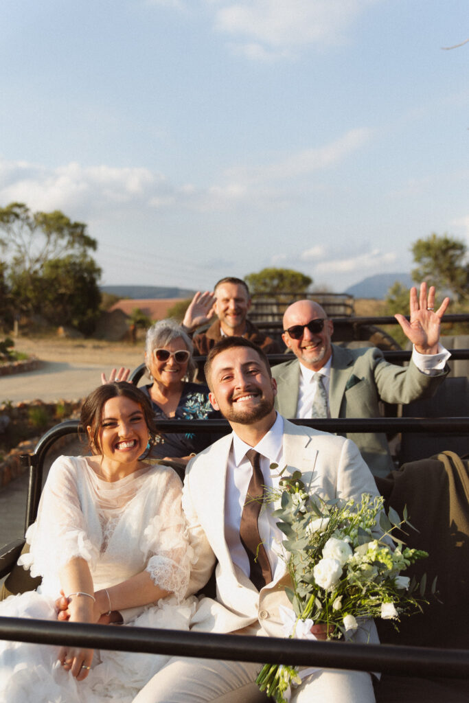 Bride and groom riding in an open safari vehicle with their parents during an intimate South Africa wedding